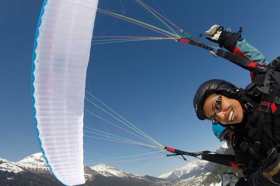 Vuelos en parapente en los Alpes con un iglú de fondo y montañas cubiertas de nieve.