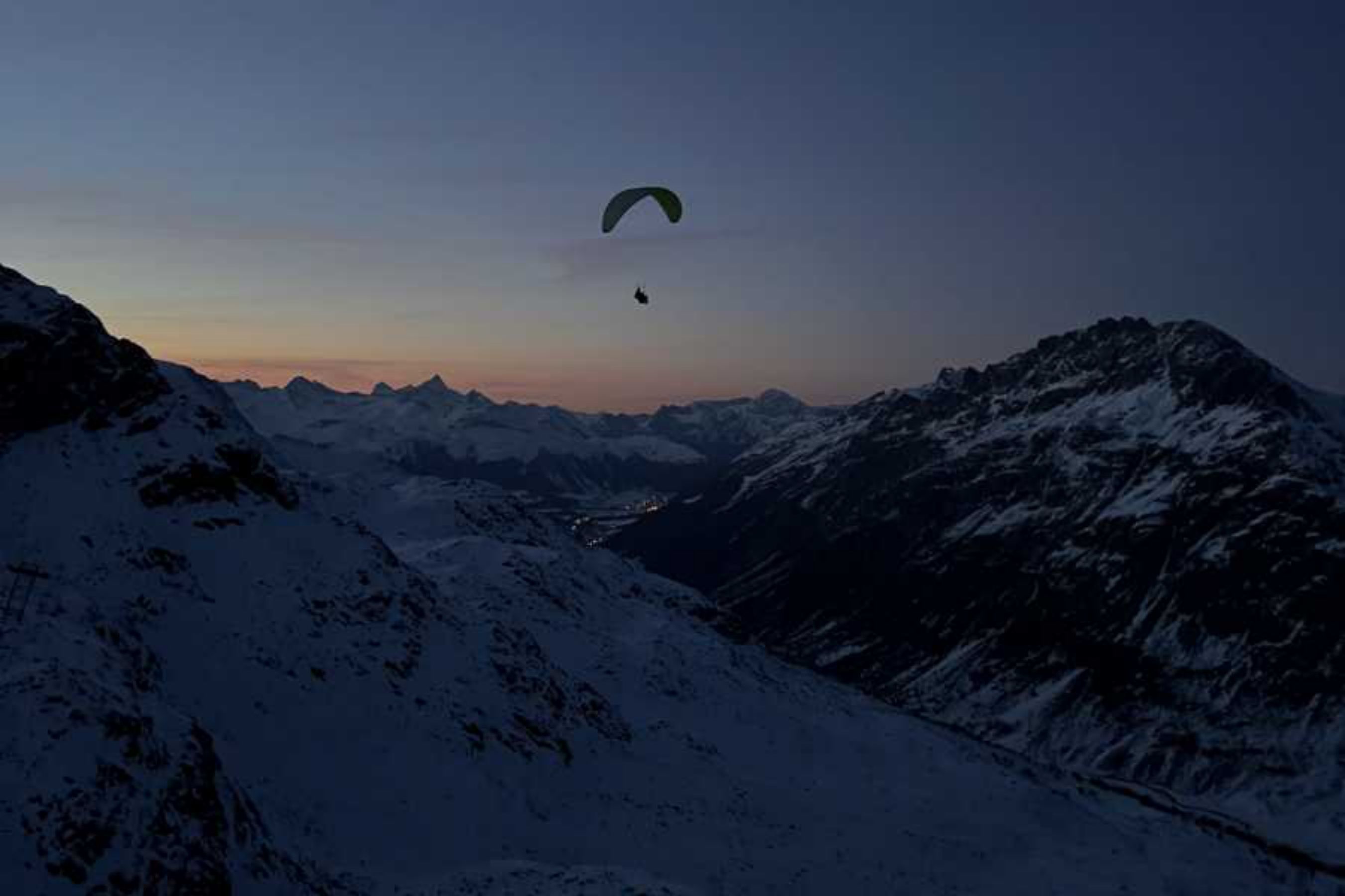 Voo da Lua Cheia: Parapente sobre os Alpes cobertos de neve à noite, a perfeita aventura de inverno nas montanhas.