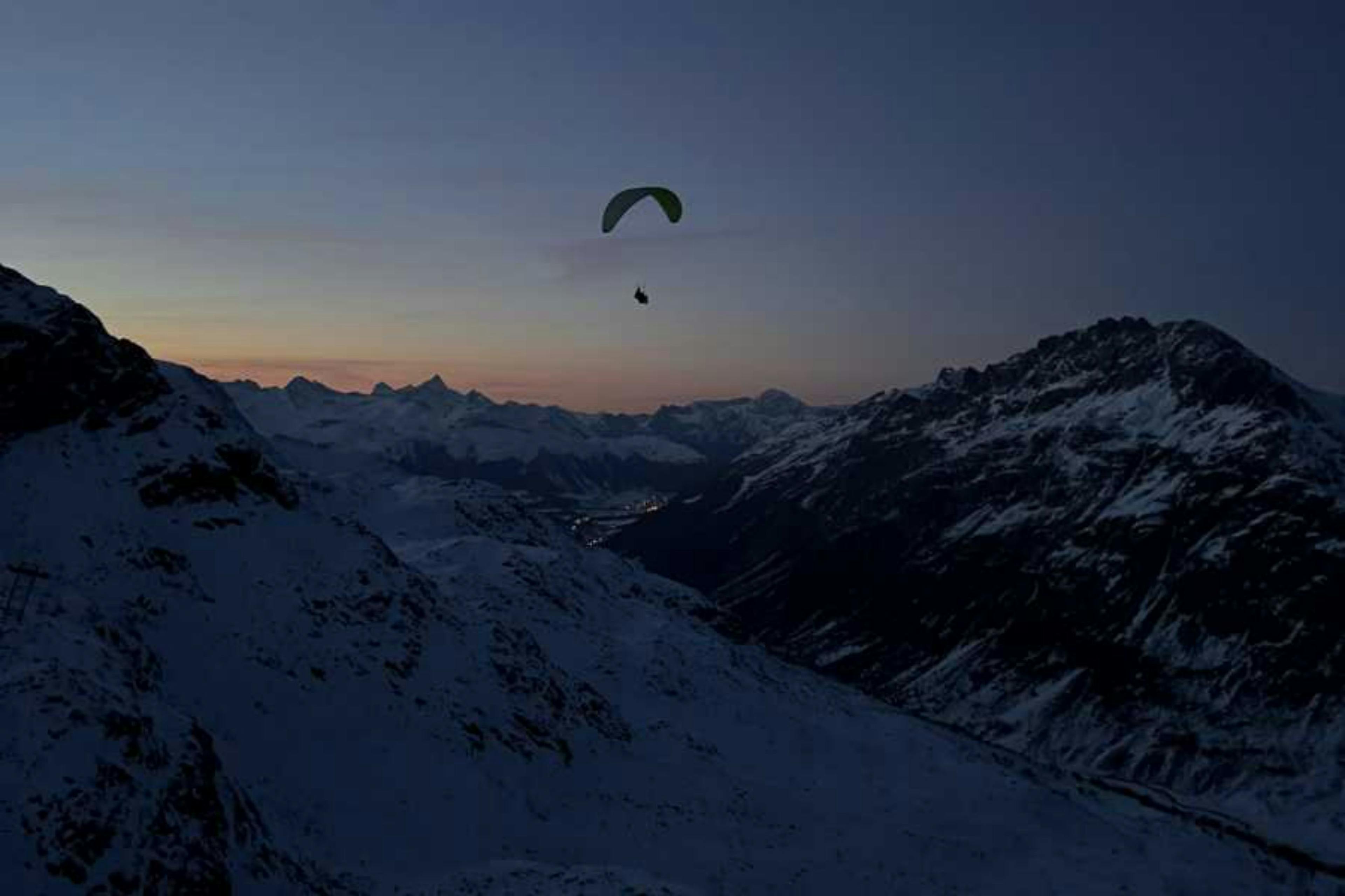 Vuelo de luna llena: Disfruta del parapente sobre montañas nevadas en la naturaleza