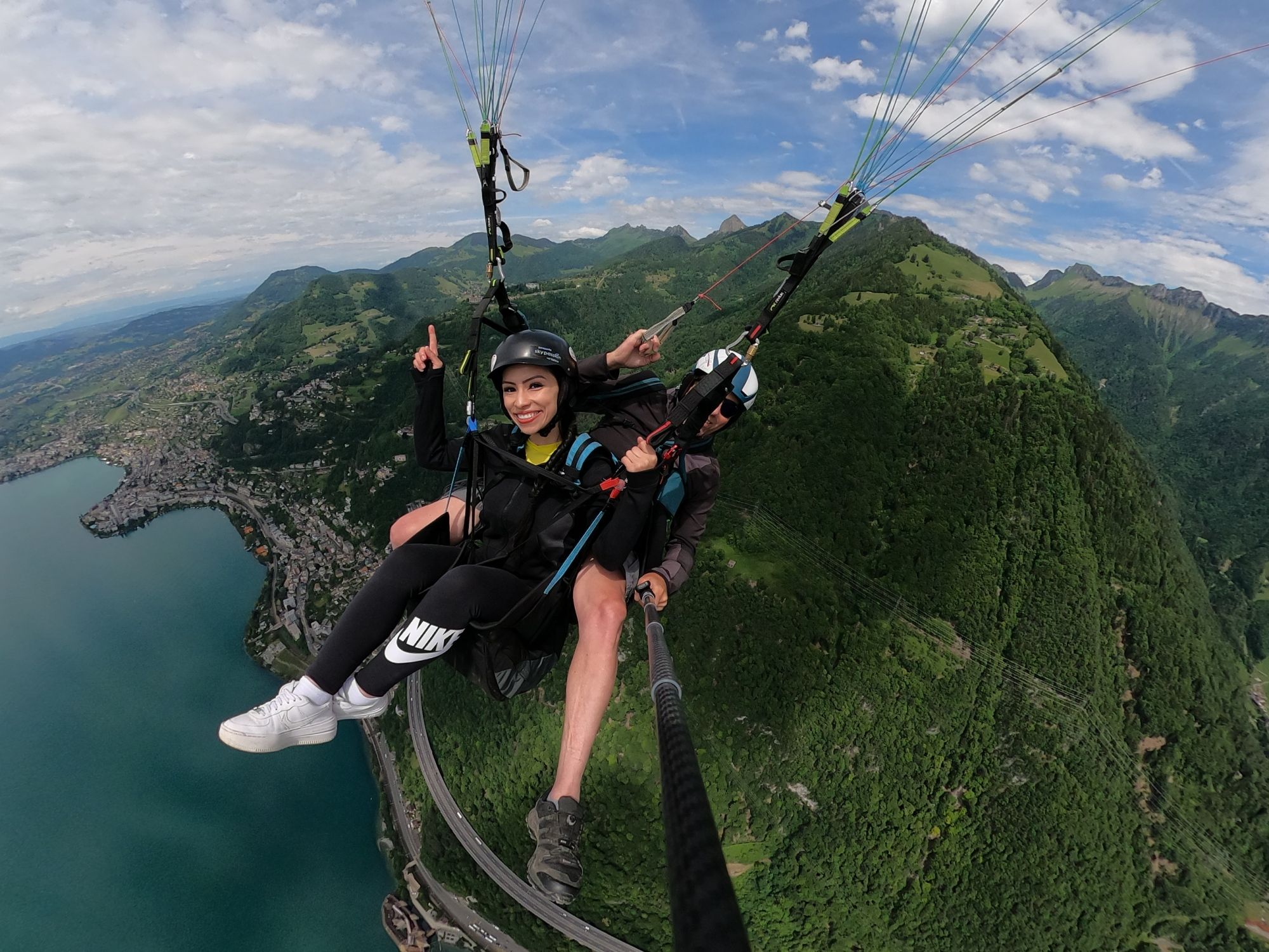जेनेवा झील के ऊपर ग्रीन्स पहाड़ों के पीछे पैराग्लाइडिंग टंडेम उड़ान