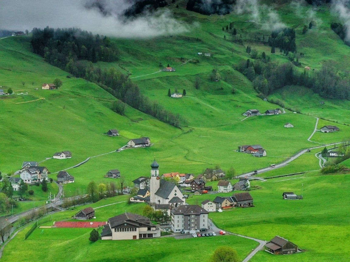 Heidi Fattoria Svizzera: paesaggio idilliaco, prati verdi, montagne e ambiente tranquillo.