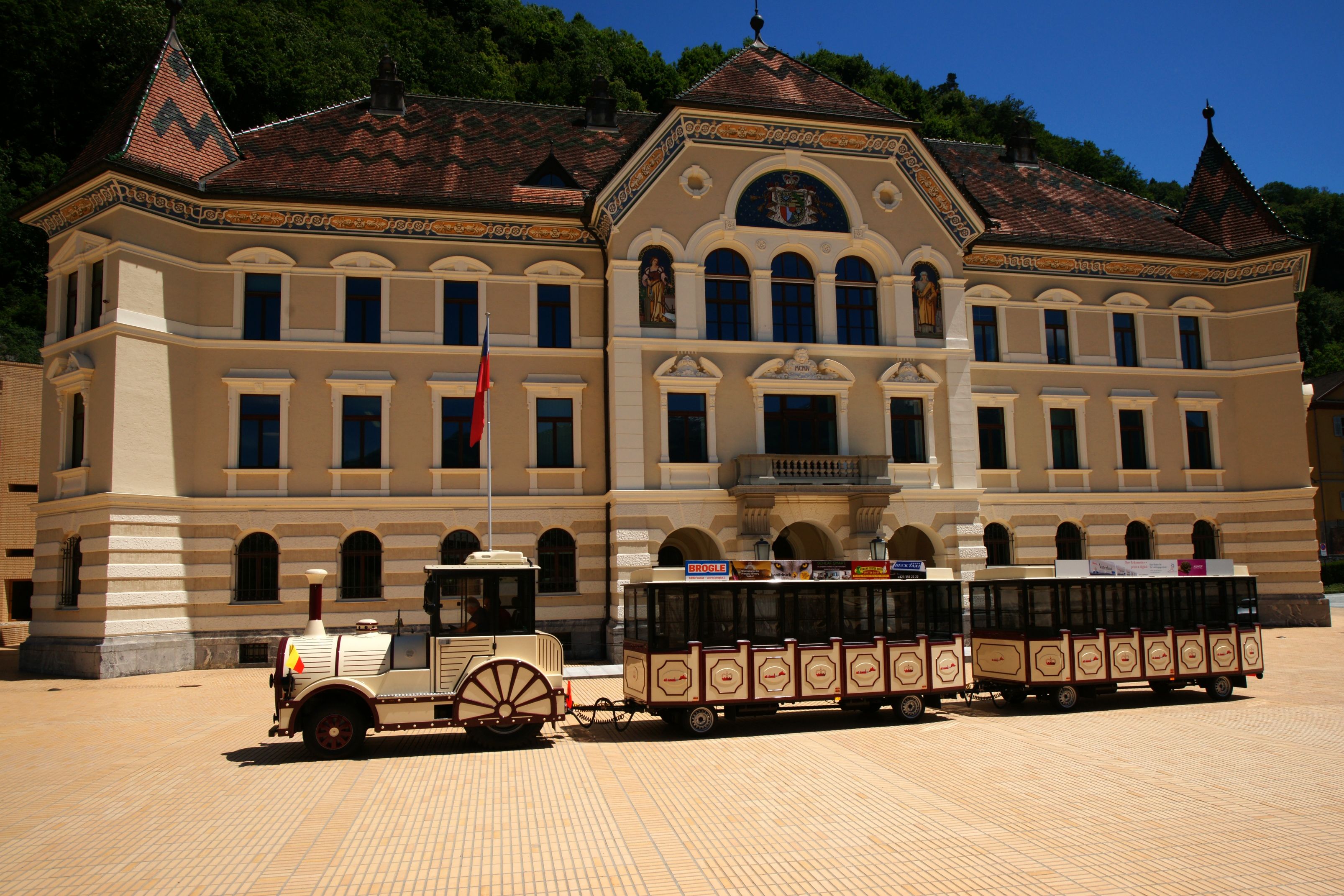 Citytrain Vaduz vor historischem Gebäude in der Hauptstadt Liechtenstein.