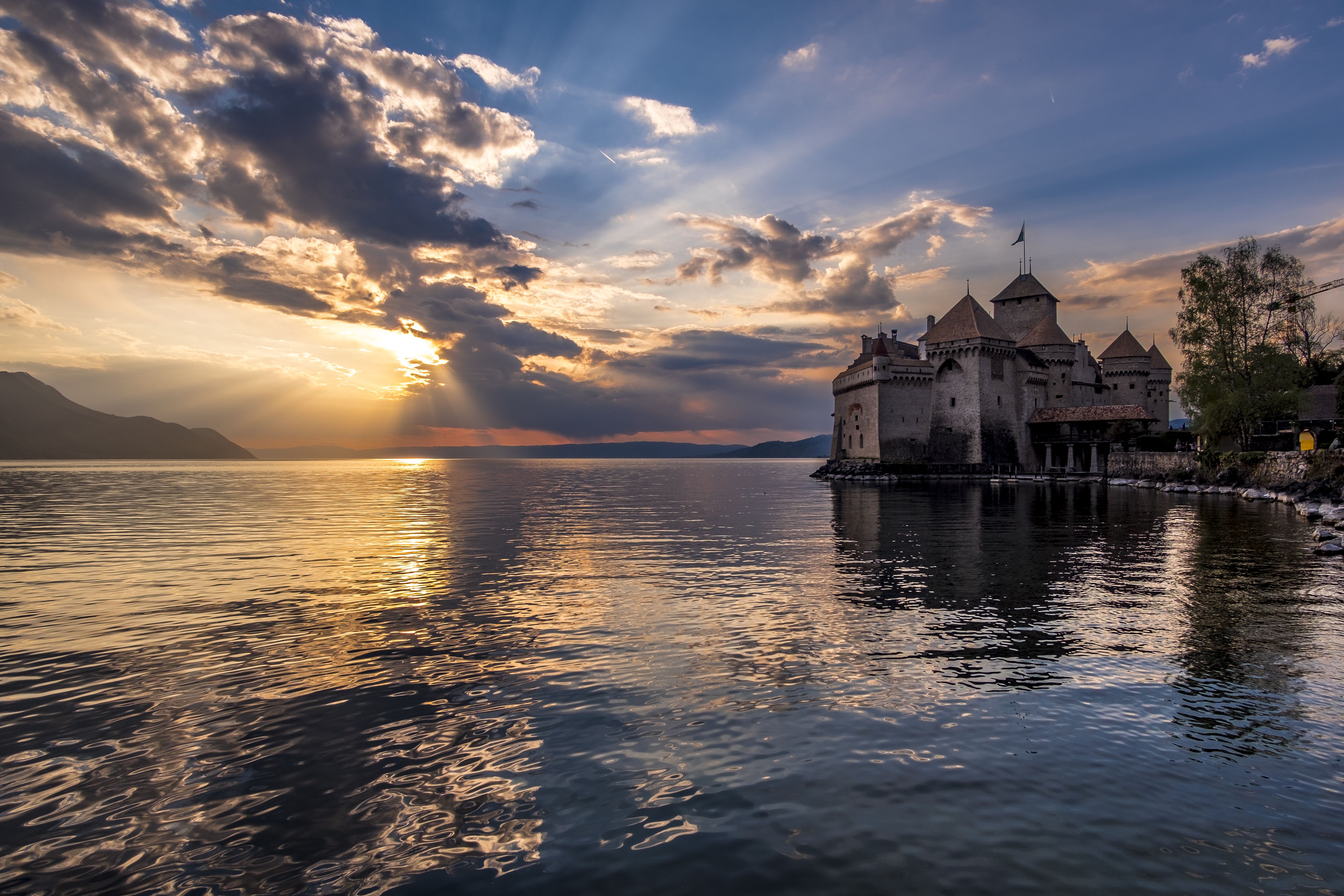 Chateau Chillon di tasik Geneva dengan matahari terbenam dan gelombang yang memantul