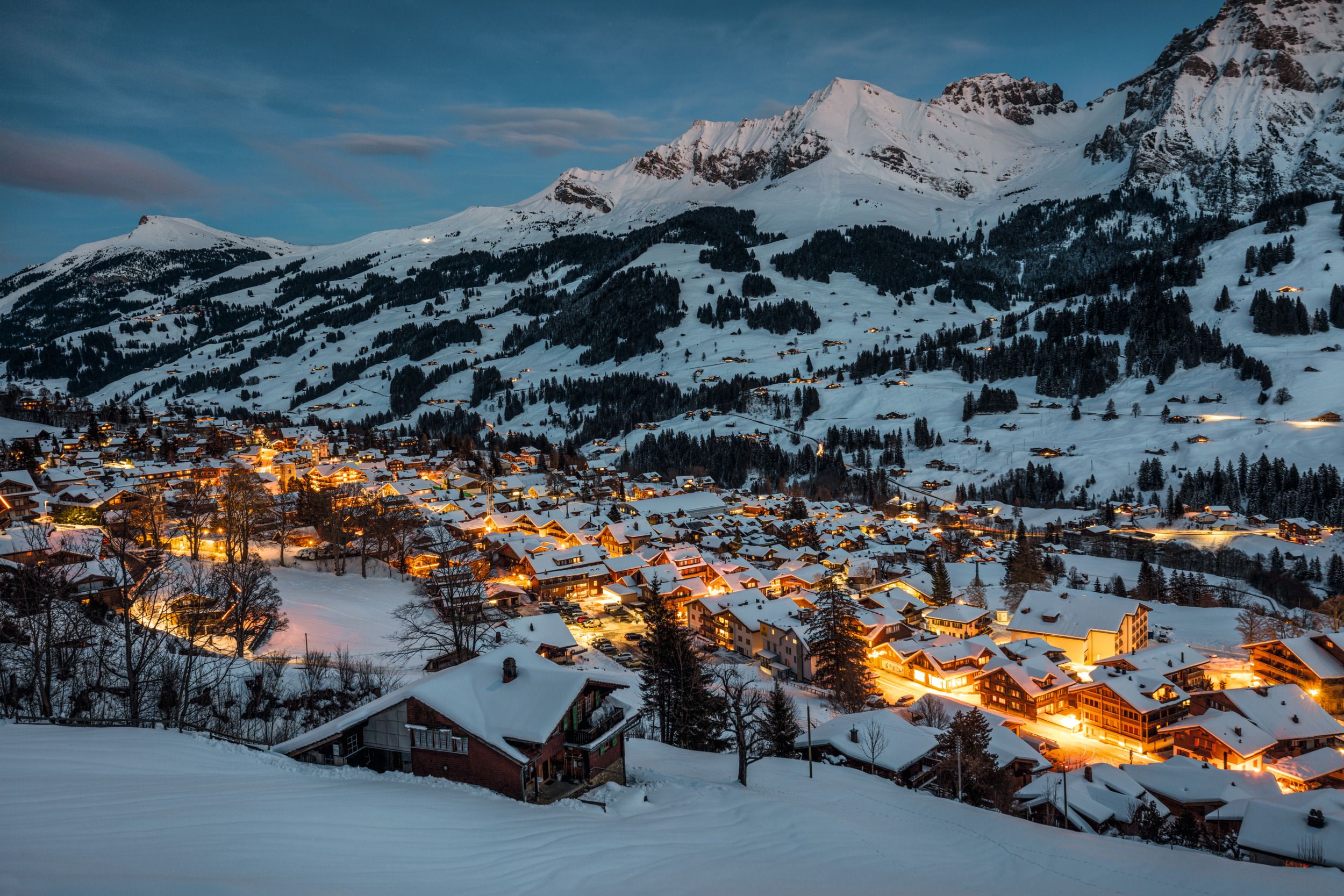 Adelboden crepúsculo com edifícios iluminados e montanhas cobertas de neve