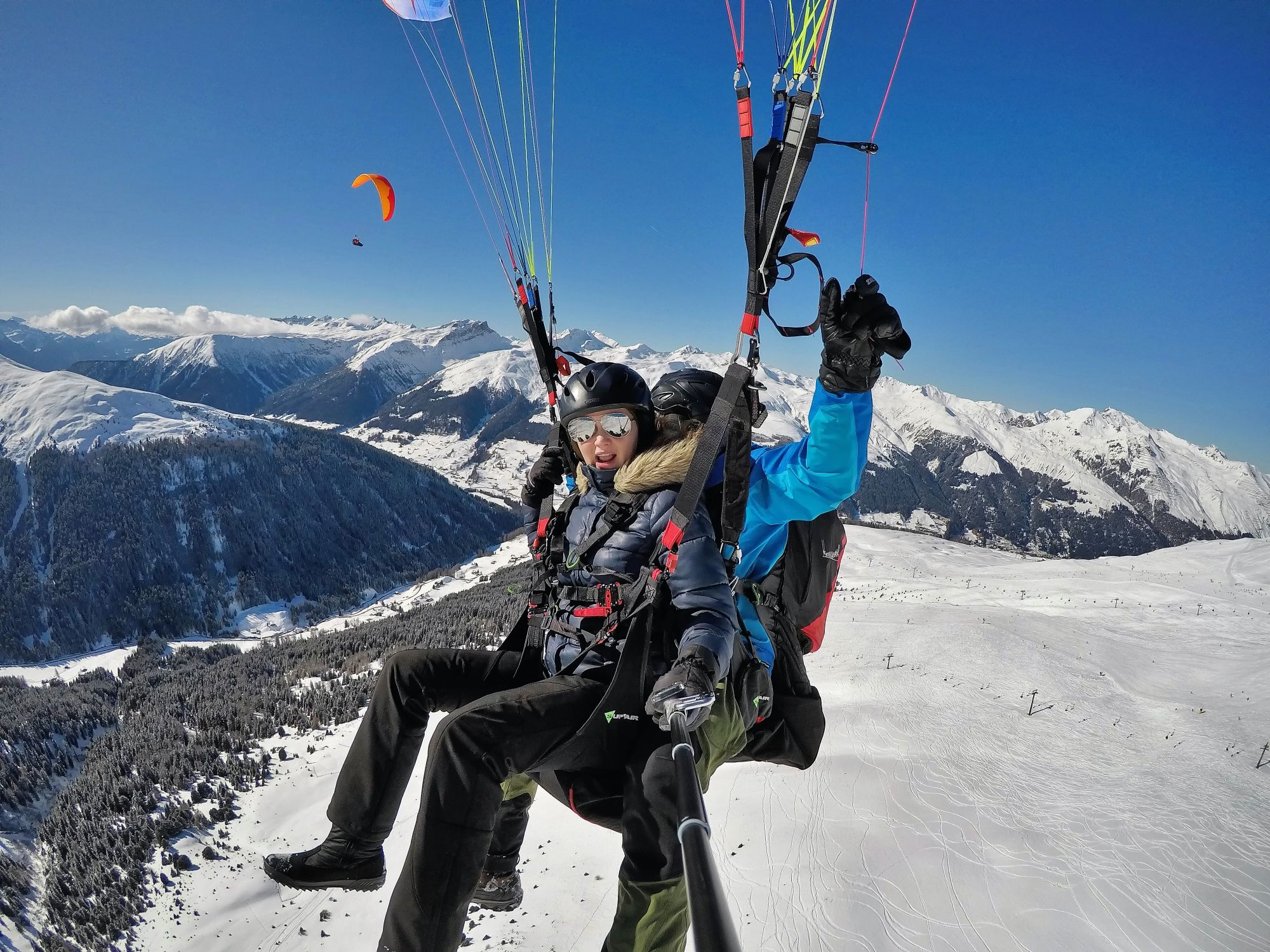 Voler en parapente à Davos pendant l'hiver, au-dessus des montagnes recouvertes de neige.