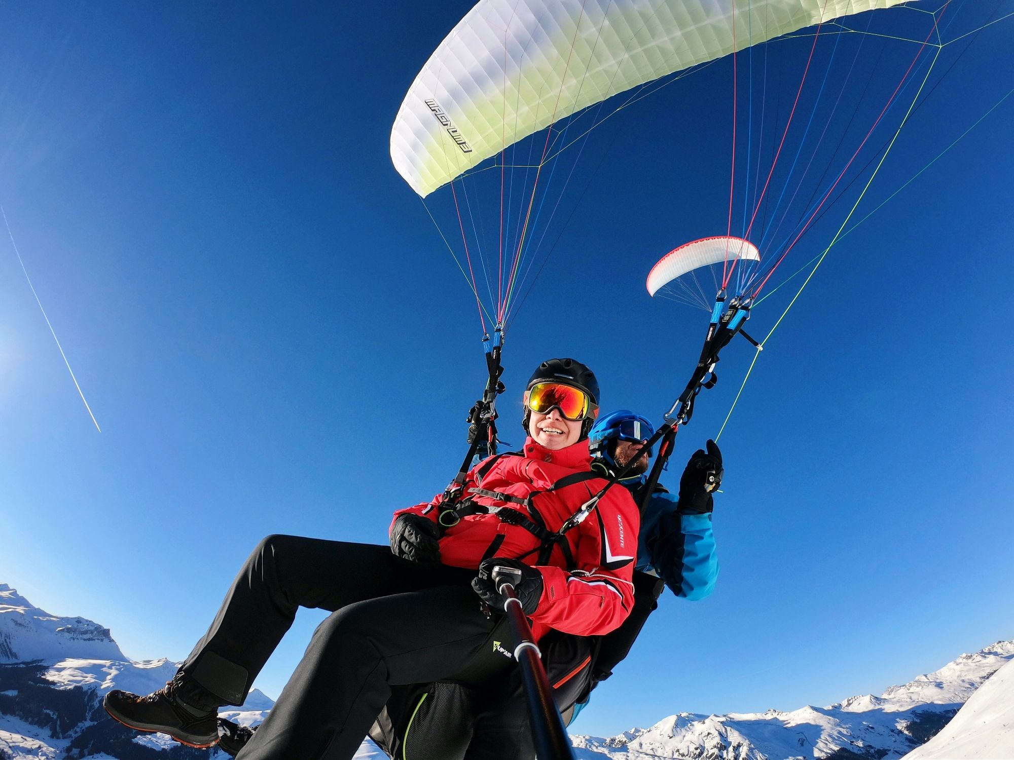 Paragliden in de winter boven Klosters, piloten met parachute en sneeuwbergen