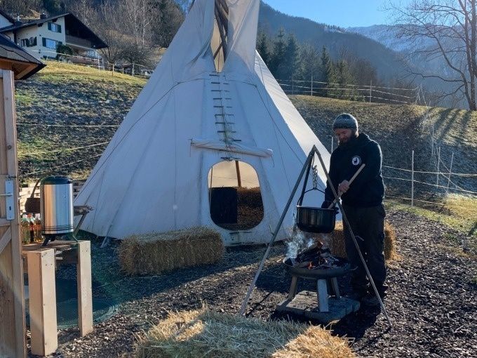 Lelaki memasak di luar berhampiran khemah dan tempat api.