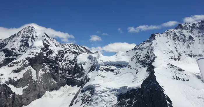 Alptradflug med helikopter över snöklädda berg och blå himmel