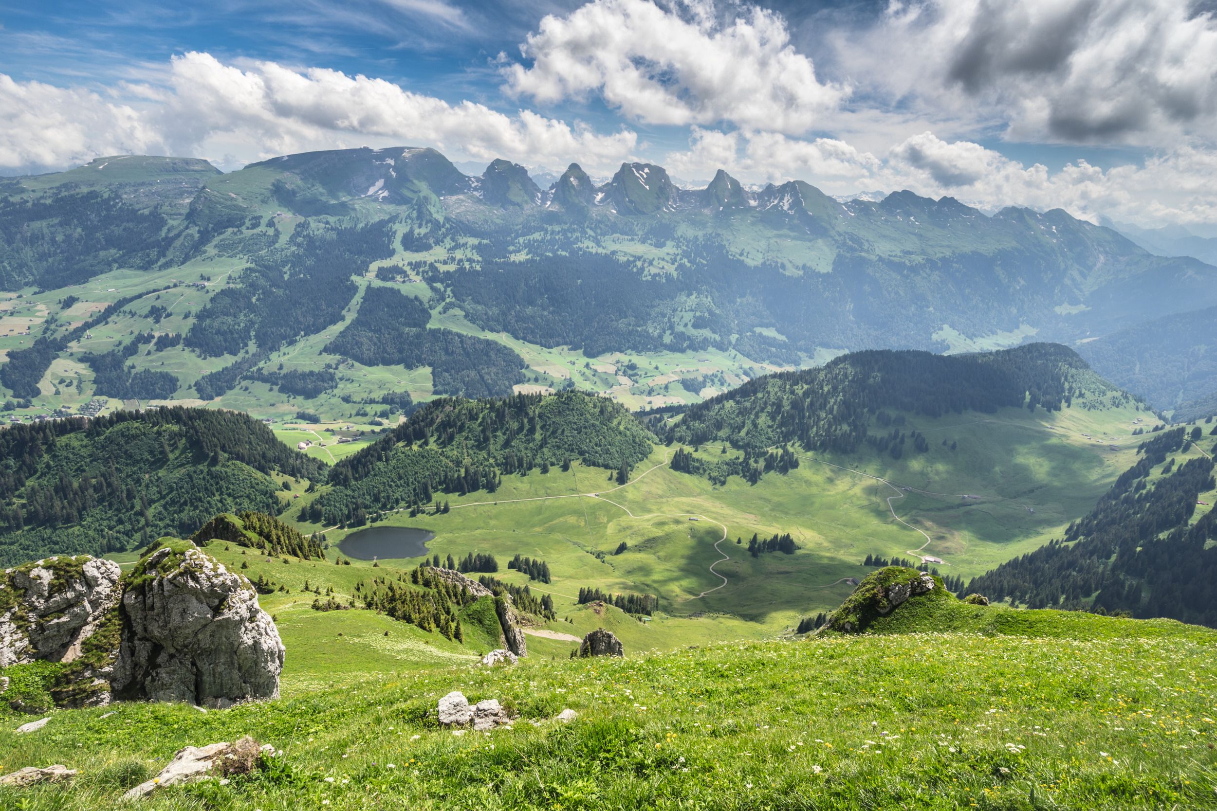 Alt St. Johann dengan pemandangan ke Alps, padang rumput hijau dan gunung di latar belakang.