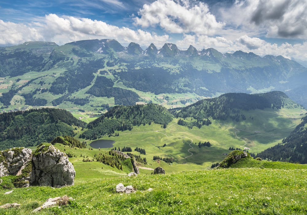 Alt St. Johann mit Blick auf die Alpen, grüne Wiesen und Berge im Hintergrund.