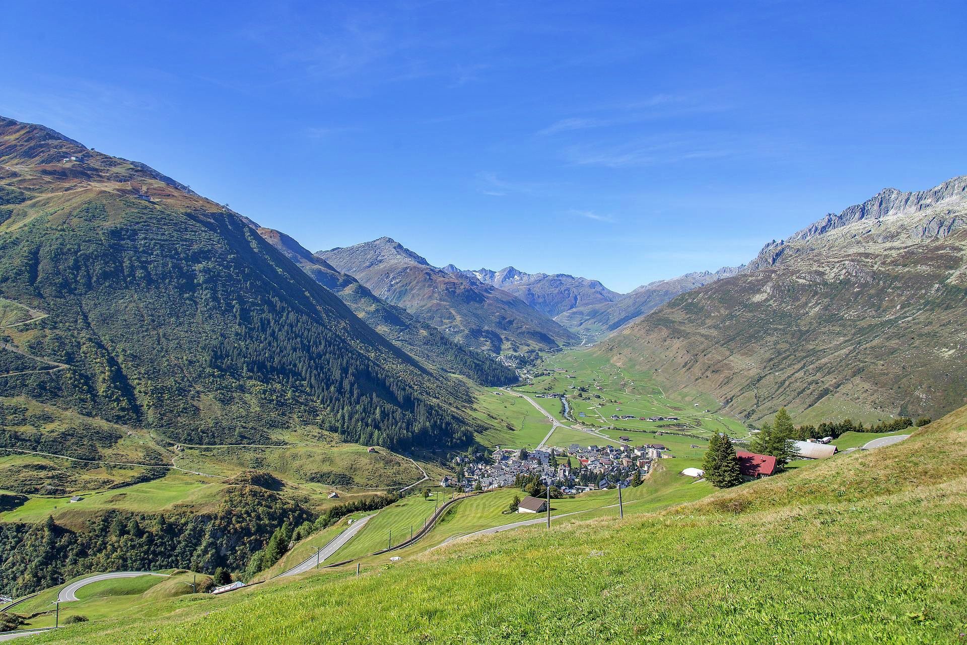 Andermatt: malerische Landschaft mit Bergen und dem charmanten Dorf im Sommer.
