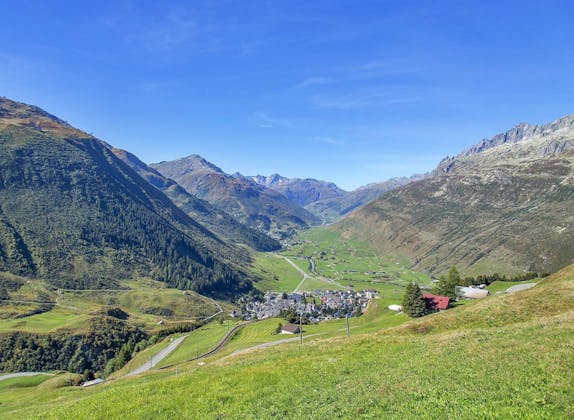 Andermatt: atemberaubende Berglandschaft mit Tal und Häusern, ideal für Abenteuer und Naturerlebnisse.