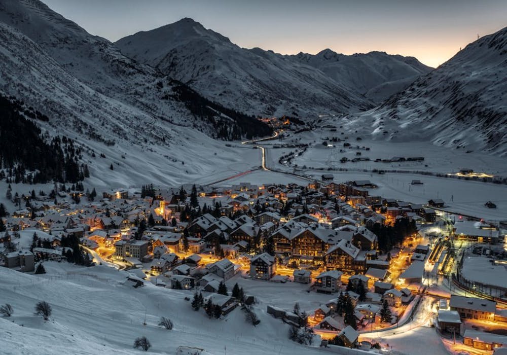 Andermatt: idyllischer Winterort mit schneebedeckten Bergen und beleuchteten Häusern in der Schweiz