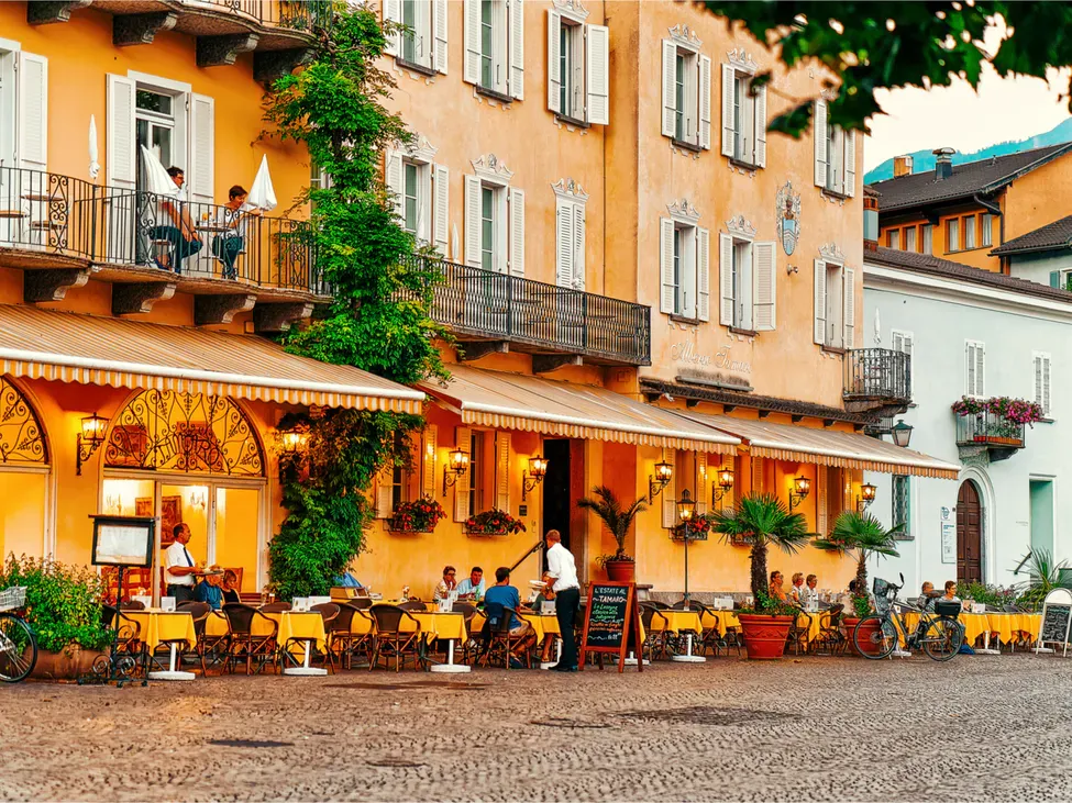 Ristorante ad Ascona con ospiti sulla terrazza, circondato da piante e luce calda