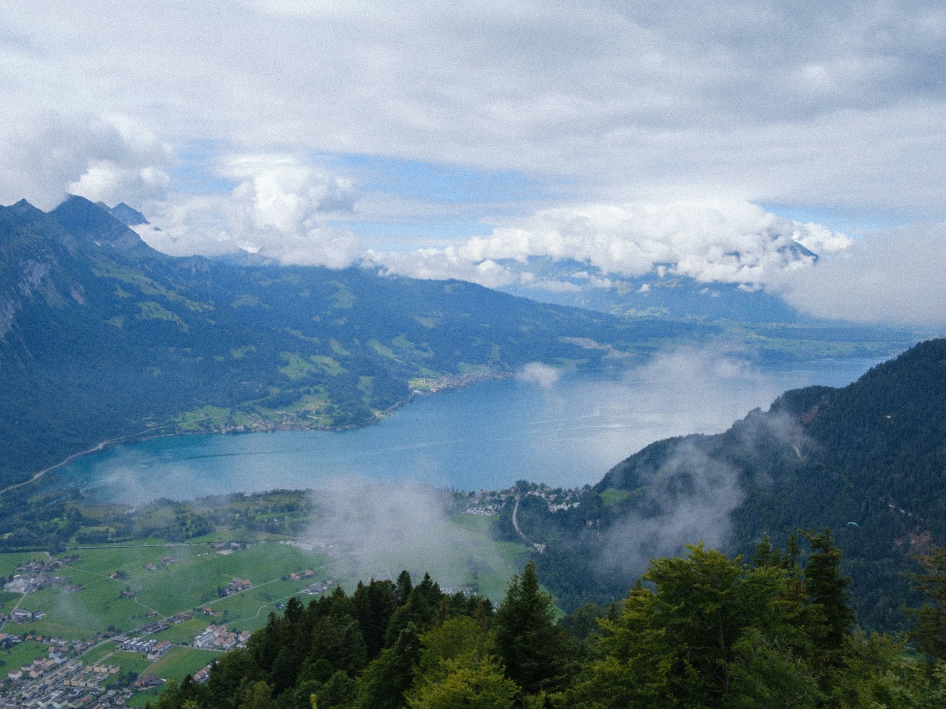 Harder Kulm: Panoramatický výhled na Thunské jezero a okolní hory za nízké oblačnosti.