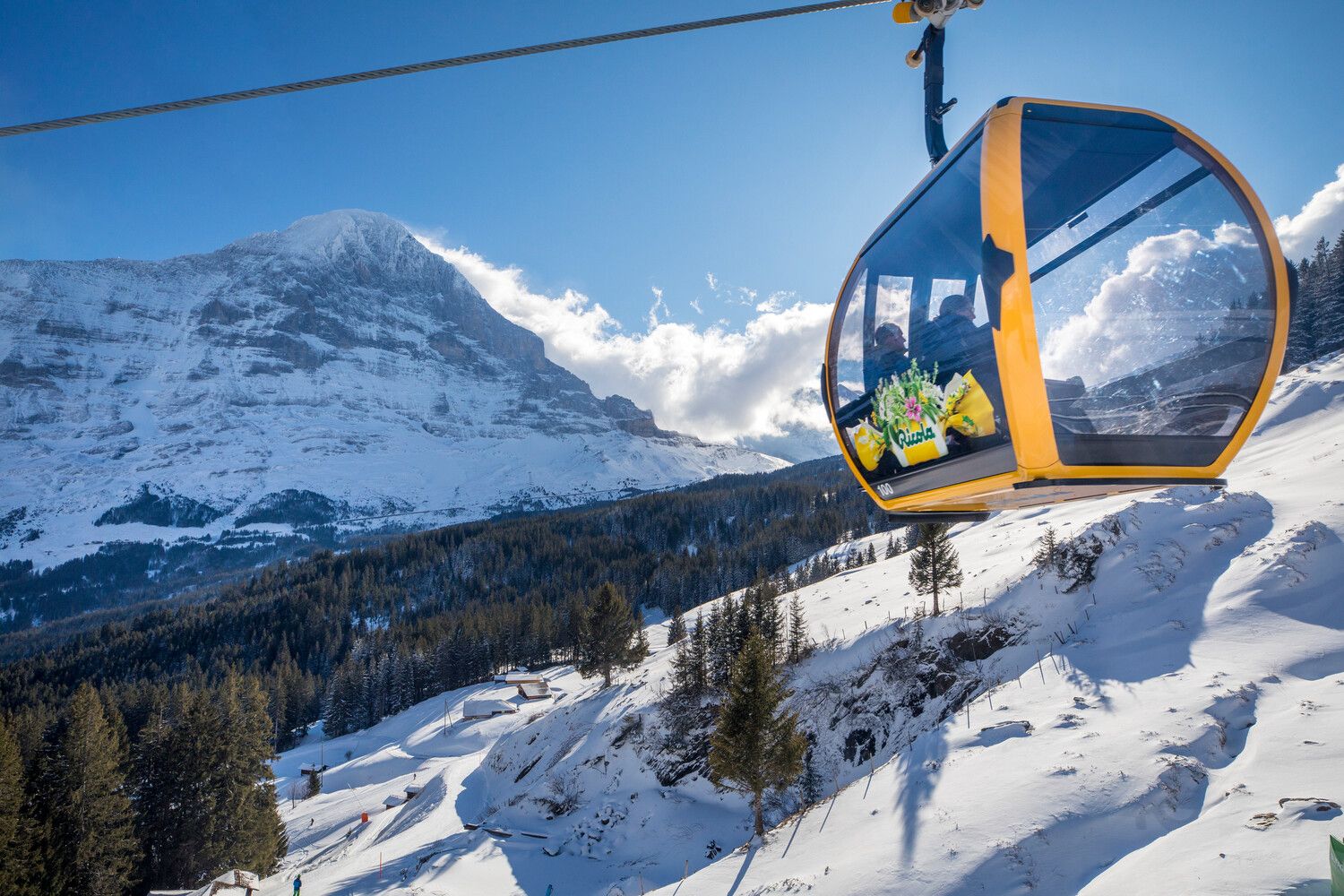 Gondelbahn in den Alpen, umgeben von schneebedeckten Bergen und Winterlandschaft.