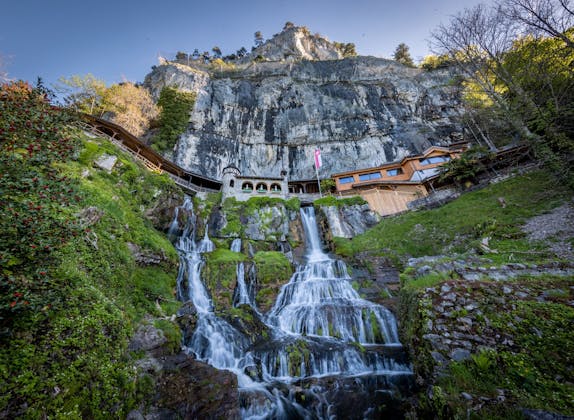 Beatus Caves: spectacular waterfall surrounded by rocks and lush nature in summer