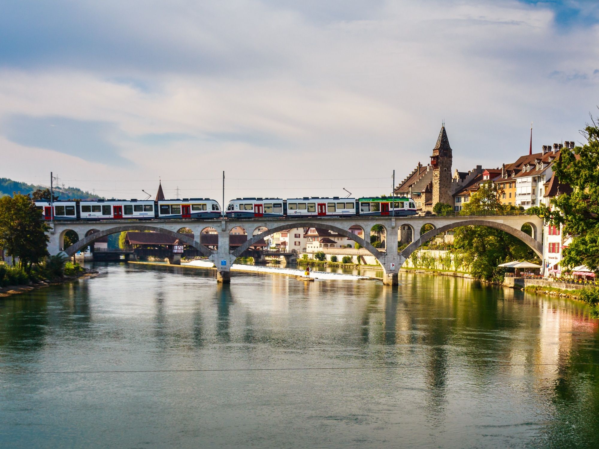 Baden Zug: Vacker bro över floden med historisk stadsbakgrund och tågfordon. Upplev staden.