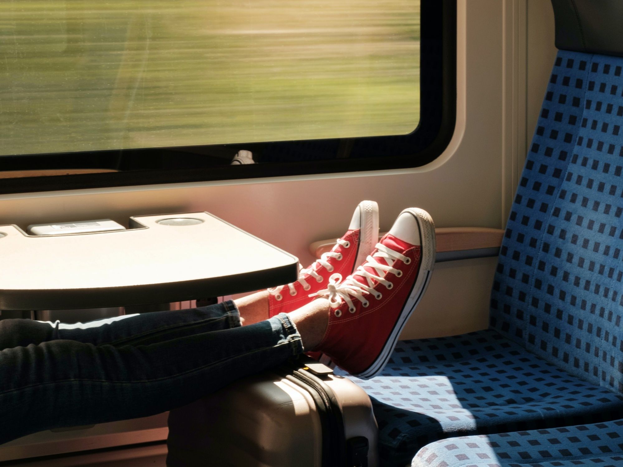列車旅行：夏の風景を楽しむ列車内で赤いスニーカーを履いたリラックスした姿勢。