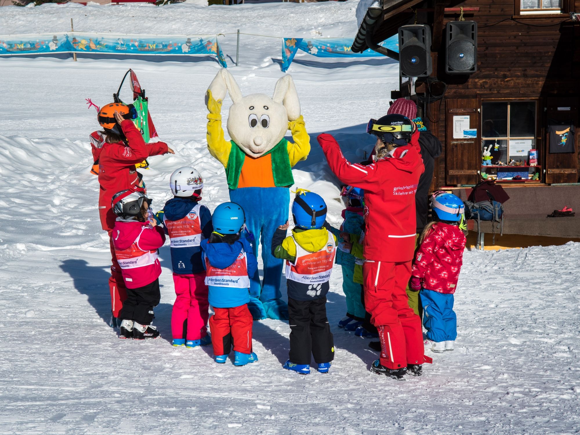 Barn som åker skidor i Grindelwald tillsammans med skidlärare och snögubbe
