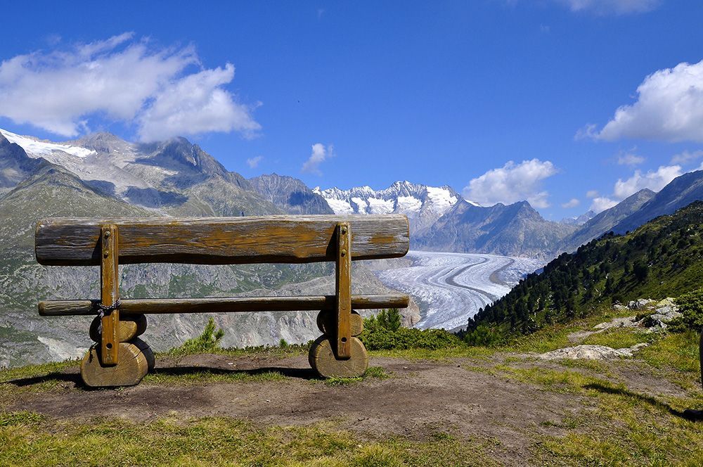 Banco en el Gran Glaciar de Aletsch con vista al glaciar, montañas y cielo.