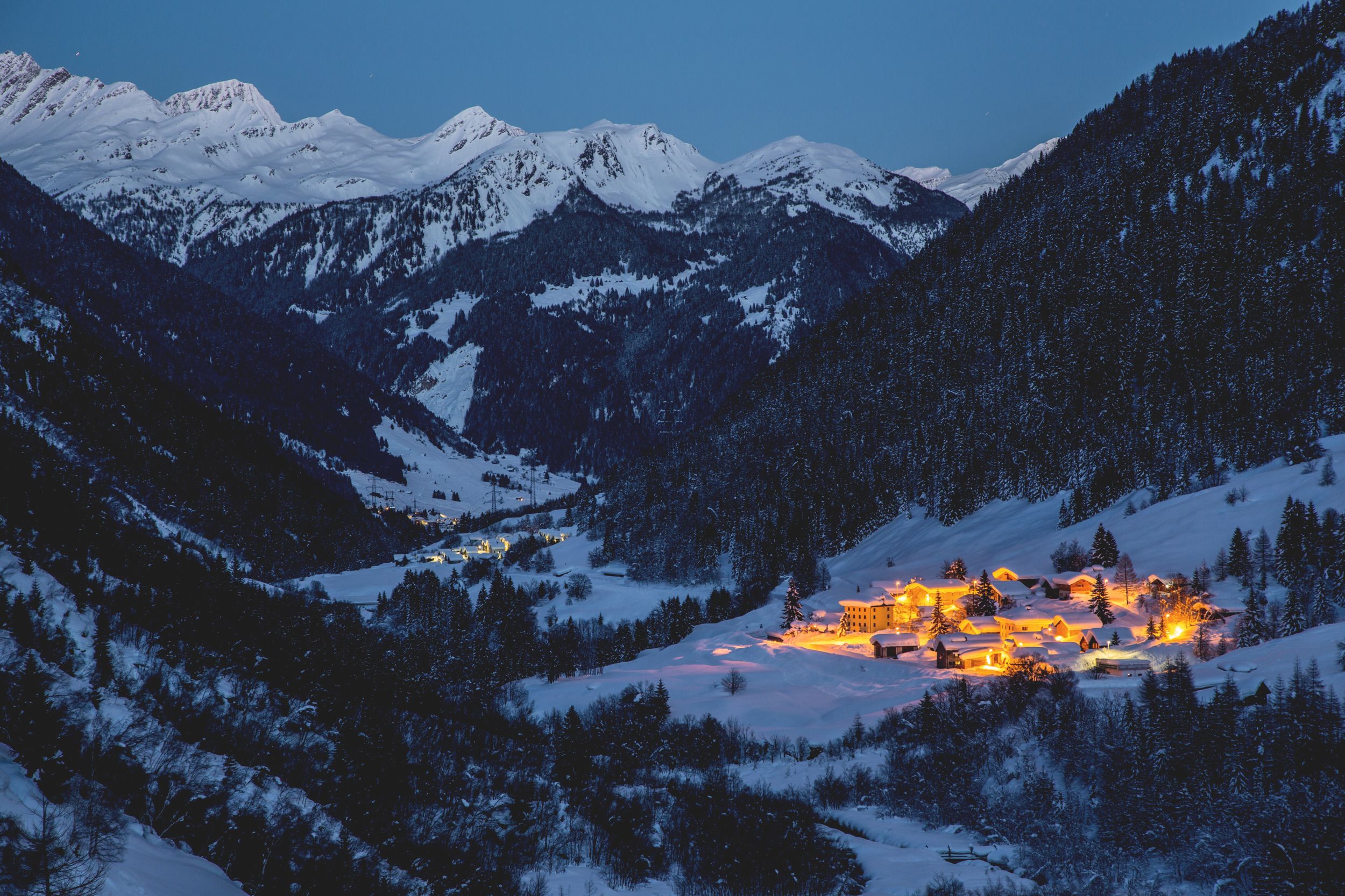 بدريتو-أوساسكو: منظر شتوي جبل مغطى بالثلوج وقرية مضاءة في الليل.