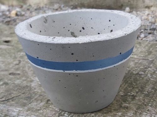 Concrete flower pot with blue stripe, conical shape, on wooden base.