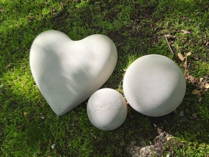 Concrete heart and balls on grass in nature.