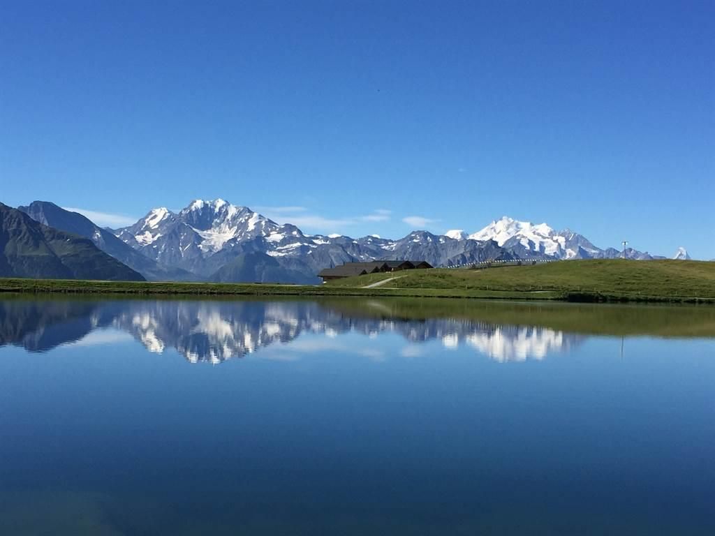 Lago Bettmer con agua refleja, montañas circundantes, cielo azul