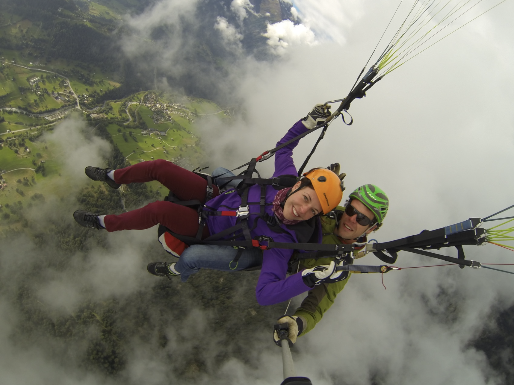 الطيران المظلي في بيلالب مع المشاركين في الغيوم فوق المناظر الطبيعية الخضراء.
