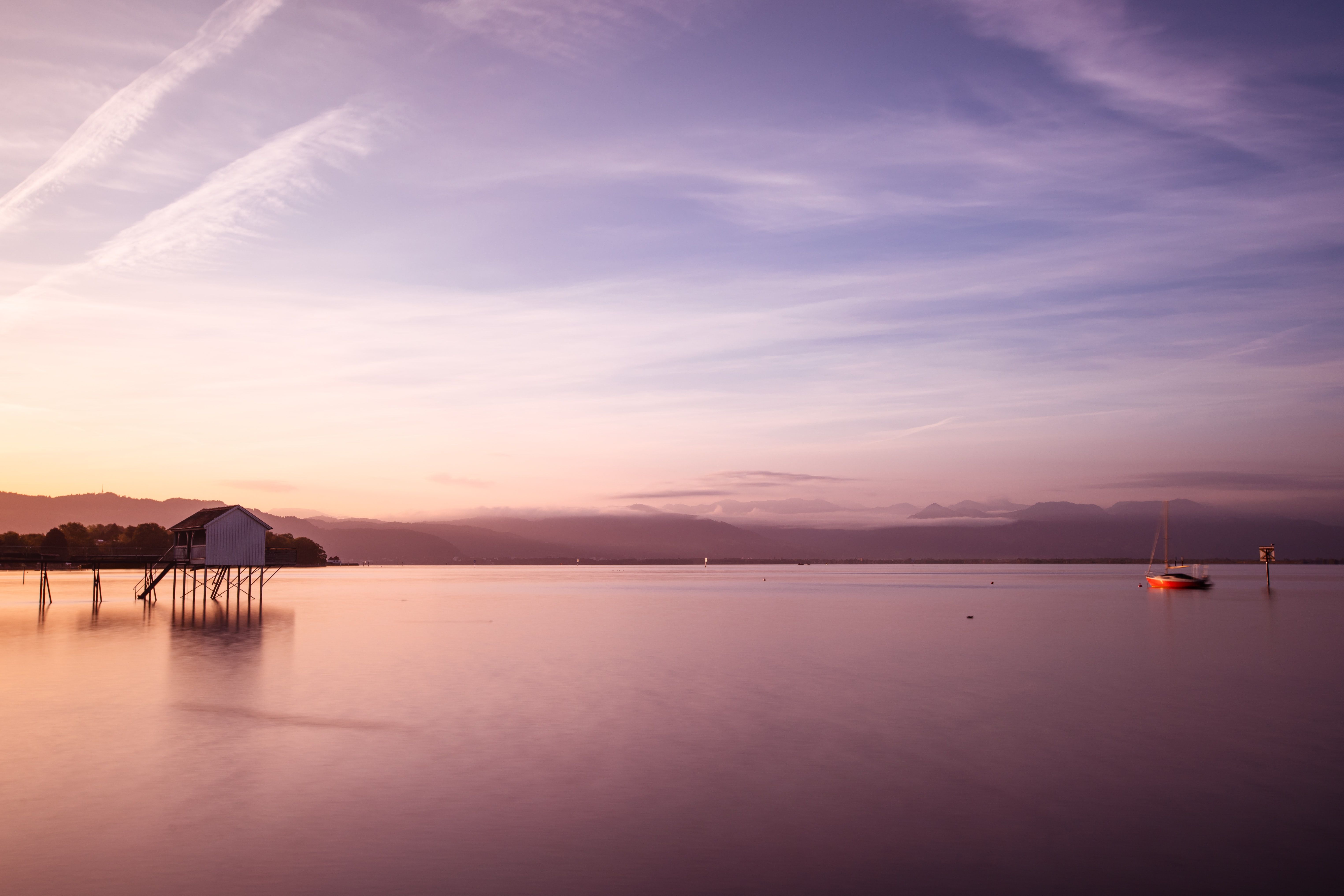Zatoka Bodensee o zmierzchu z łodzią i pomostem w Romanshorn.