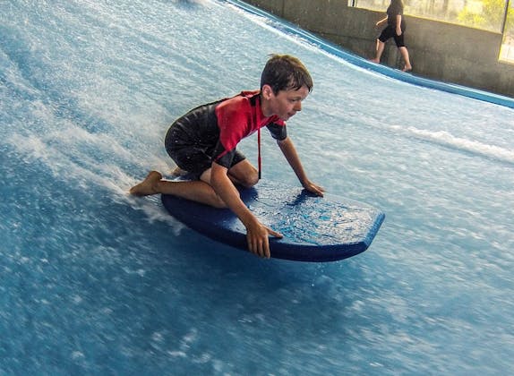 Bodyboarding Xstream: Kids surfing on an indoor wave, fun and action in the summer.