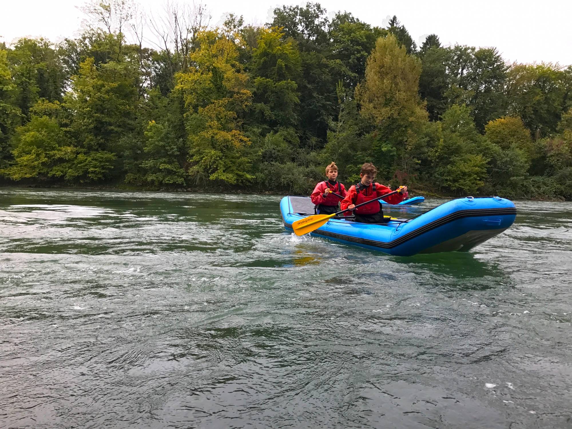 Kajakfahrt auf der Reuss mit zwei Personen in Rot, umgeben von Bäumen und Wasser