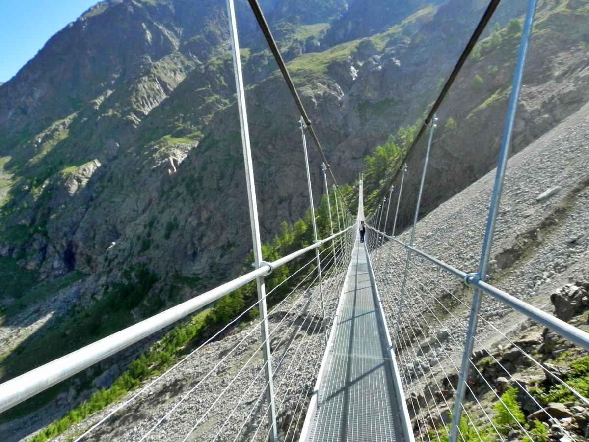 Most nad rzeką w Randzie, wysokie góry w tle, słoneczny dzień, wędrowiec na ścieżce.