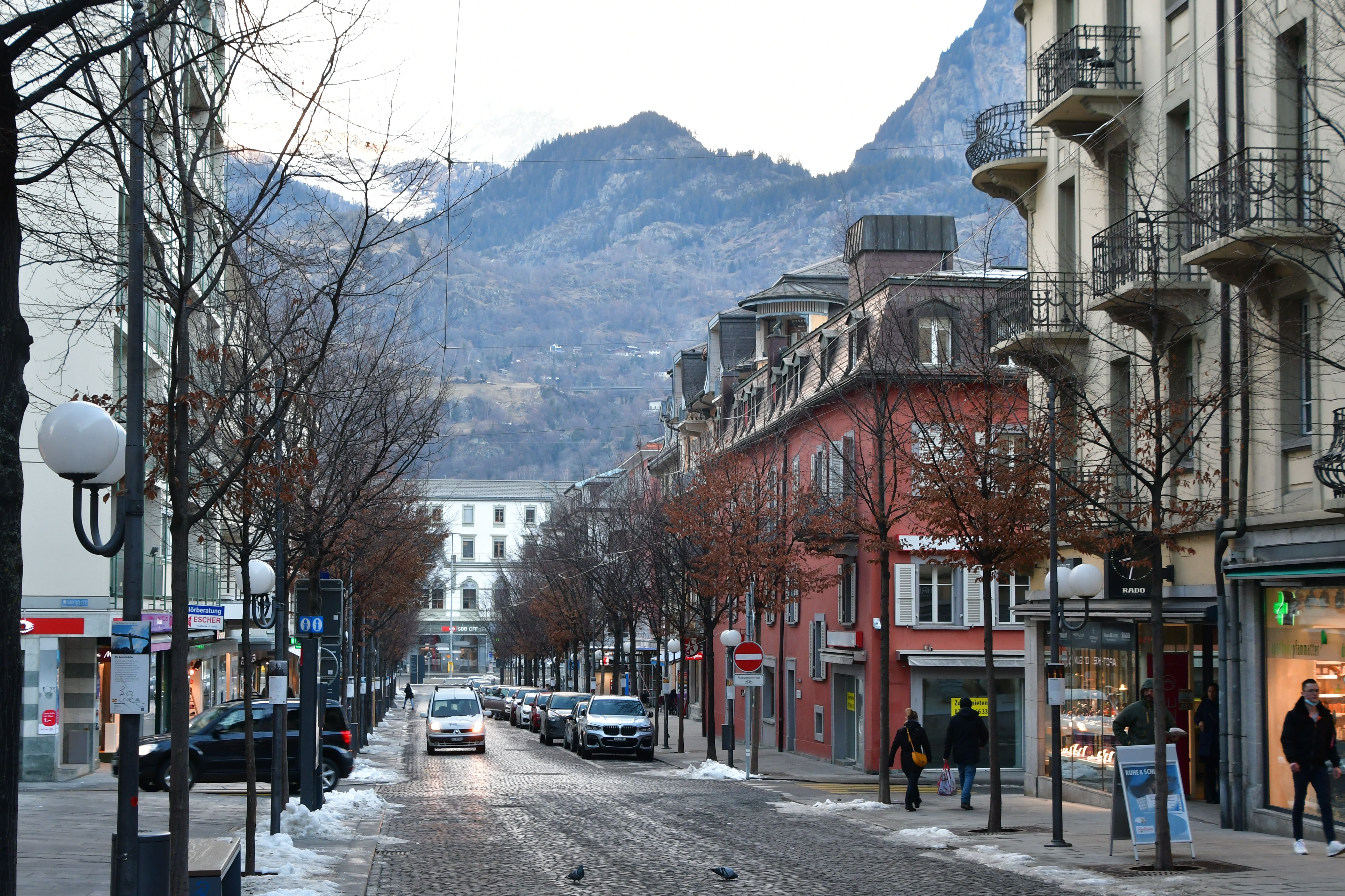 눈 덮인 산들이 배경인 도시 거리, 겨울 산책에 이상적입니다.