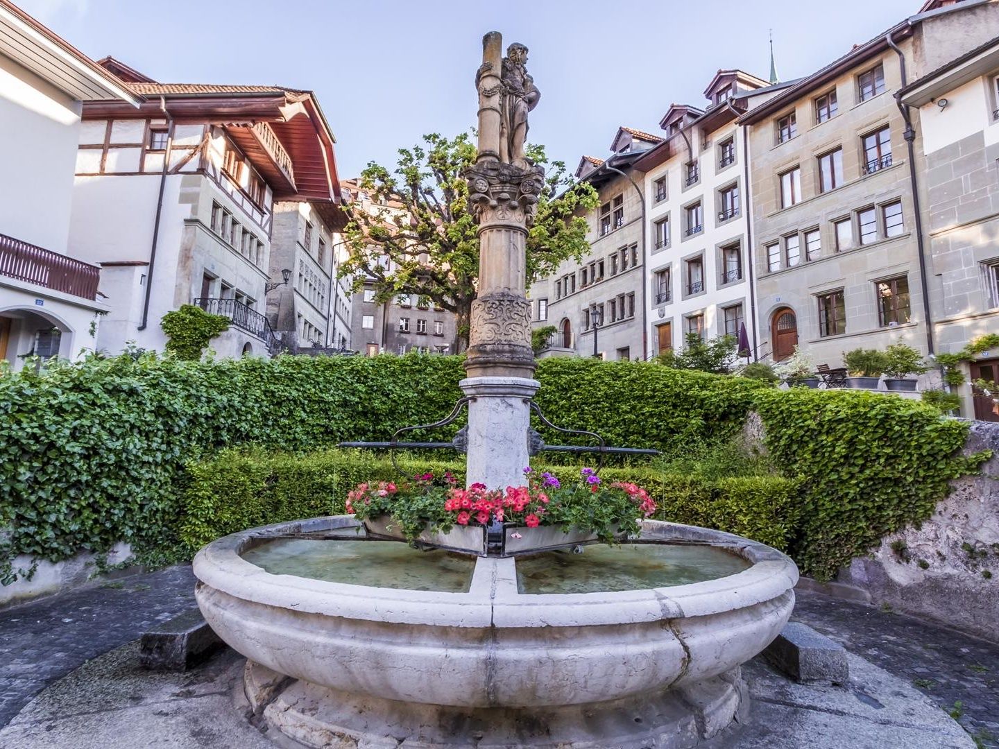 น้ำพุในฟริบูร์กับดอกไม้และอาคารประวัติศาสตร์