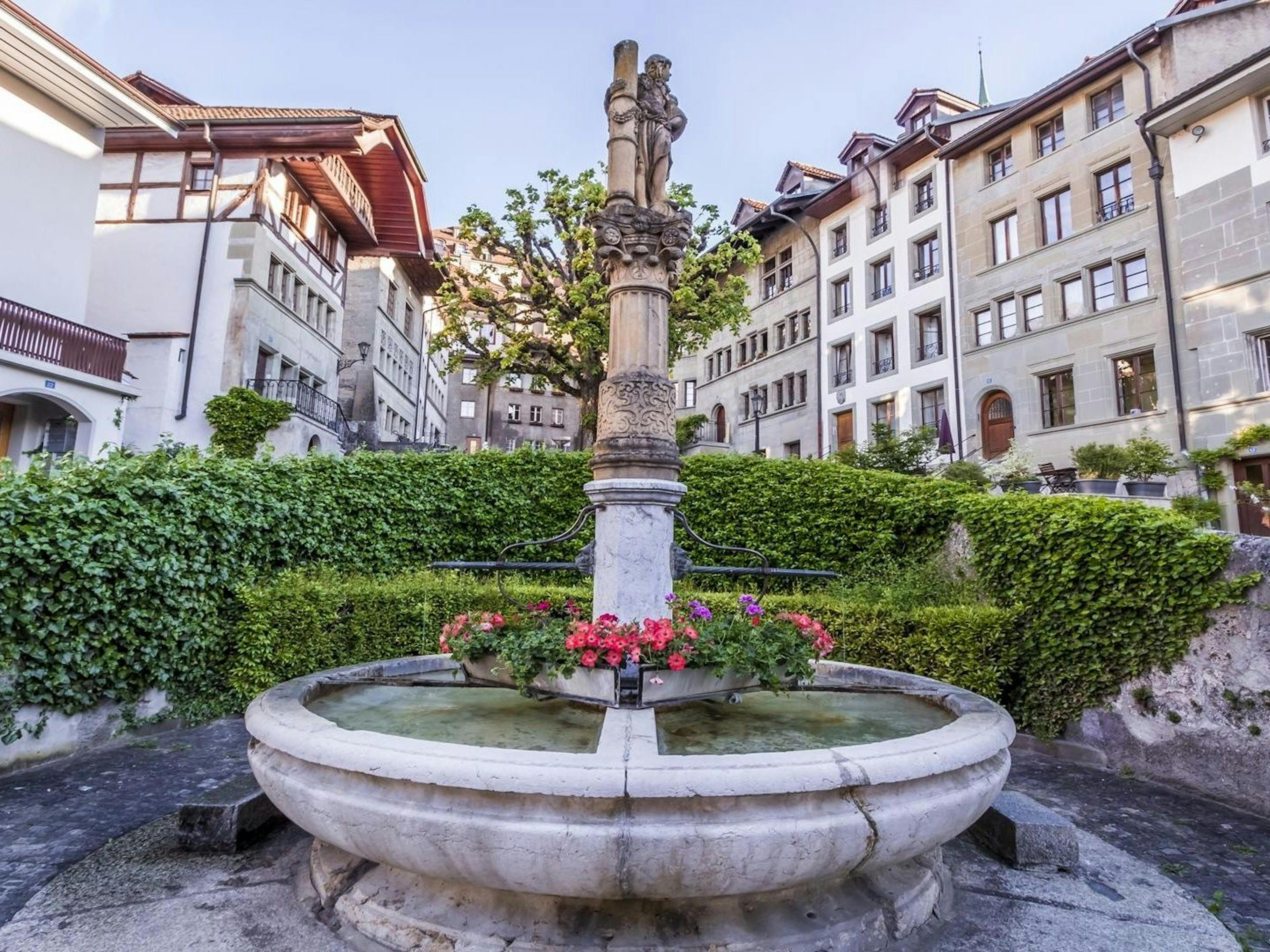 Sumur di Fribourg dengan bunga dan bangunan bersejarah