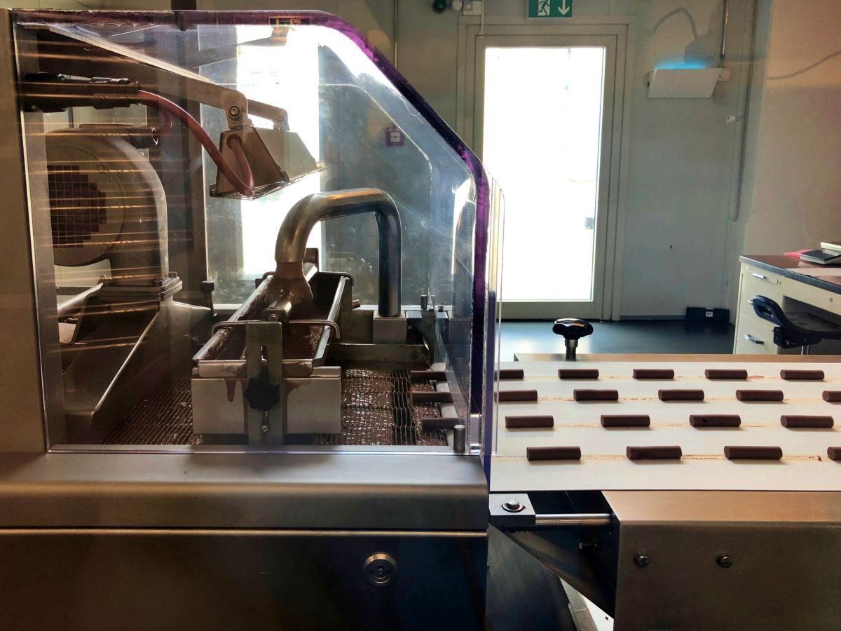 Cailler chokoladeproduktion i besøgscentret med chokoladestykker på transportbåndet.