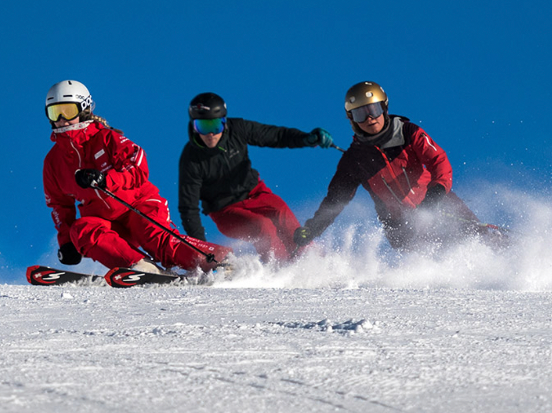 Bermain ski Grindelwald: Tiga pemain ski di atas salju segar, langit biru.