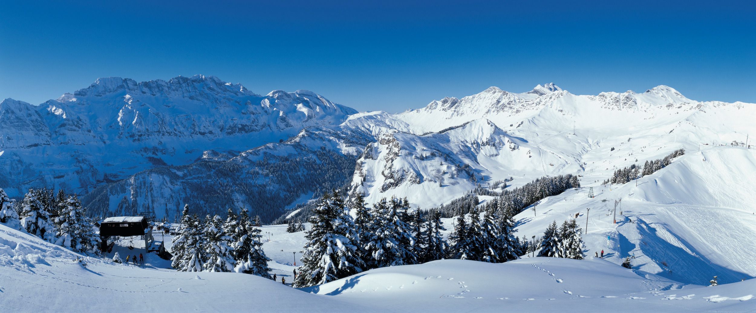 Switzerland Tourism: Winter landscape with snow-covered mountains and skiers in Switzerland