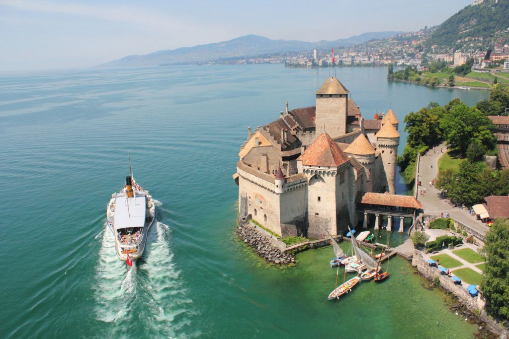 Castello di Chillon sul Lago di Ginevra con barca e ambiente verde nel 2023.