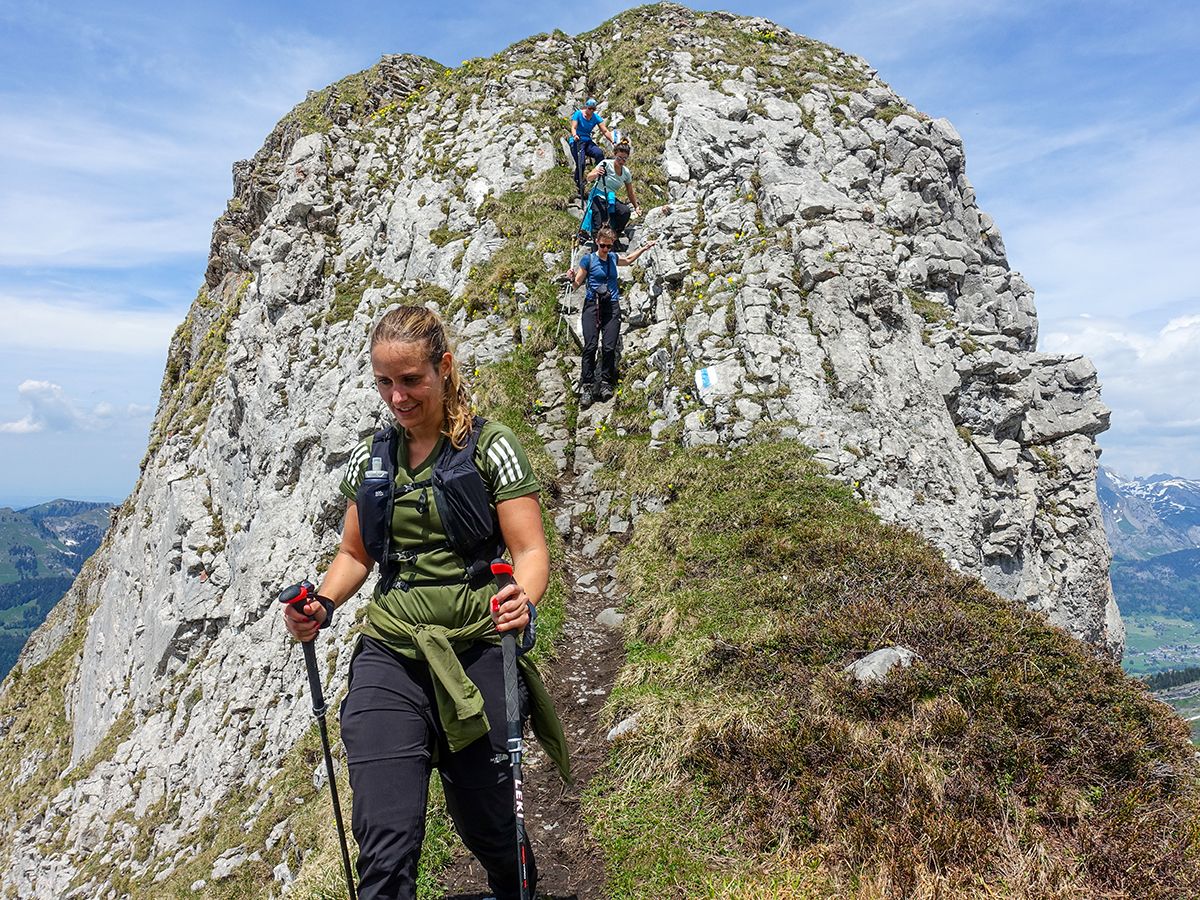 Churfirsten-turen för kvinnor när de vandrar på en stenig stig i de schweiziska bergen.
