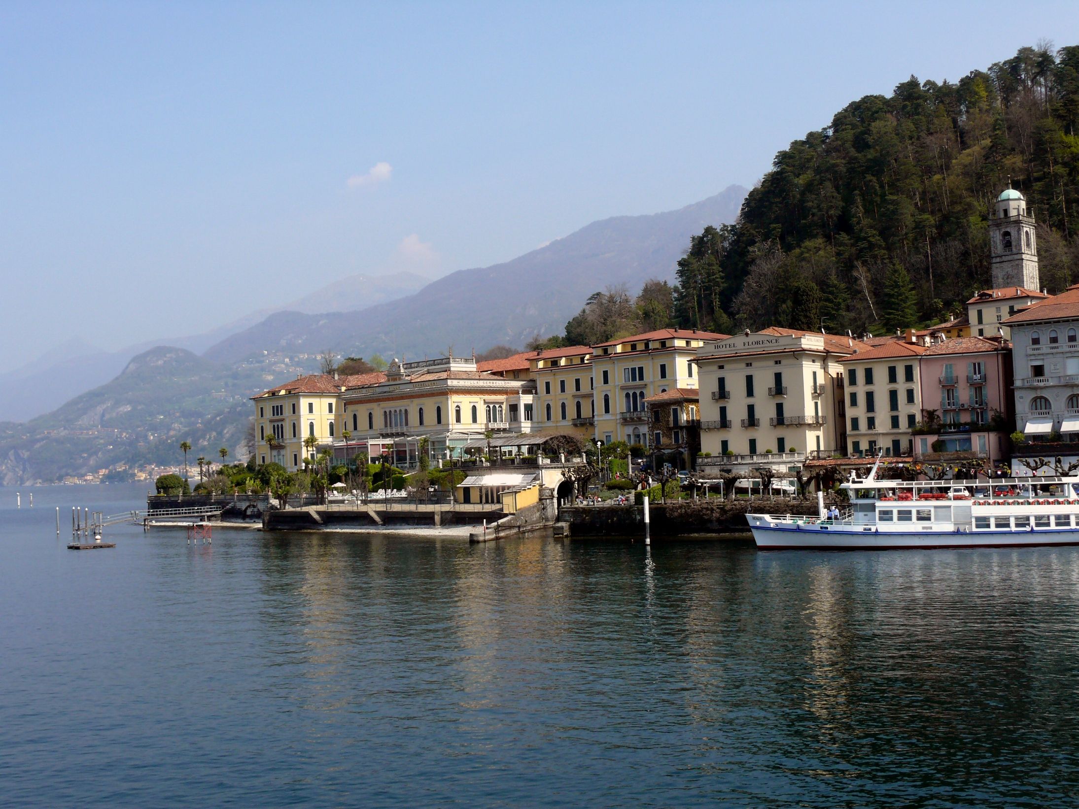 कंपेर झील: बेलाजियो में मनोहारी किनारा मार्ग पुराने भवनों और जल गतिविधियों के साथ।