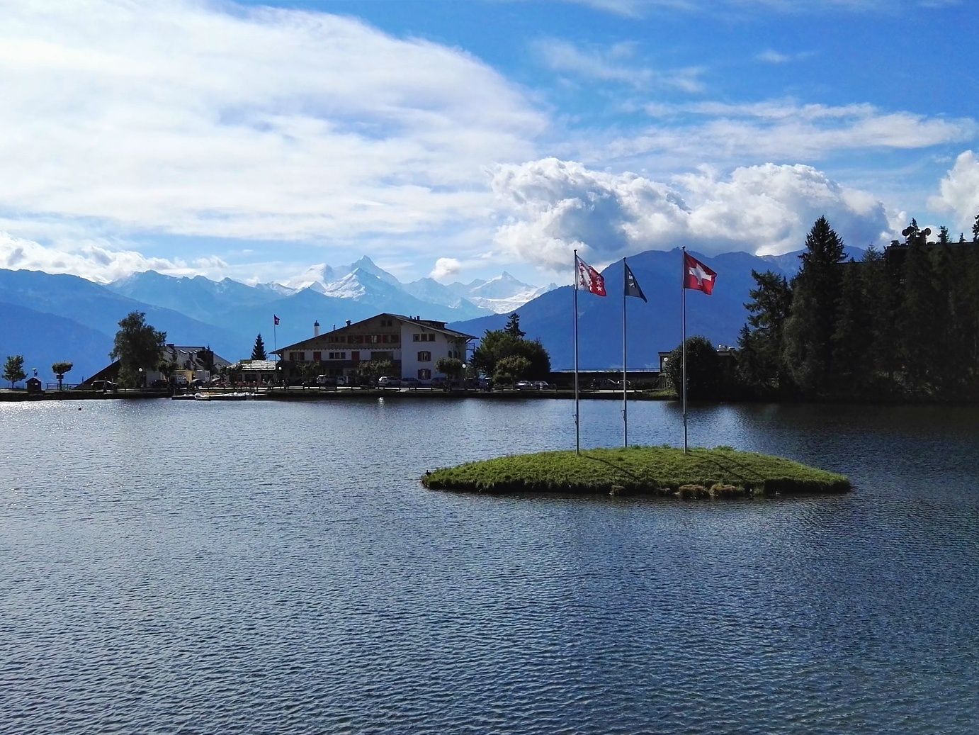 Crans Montana dengan pemandangan tasik dan gunung, bendera berkibar