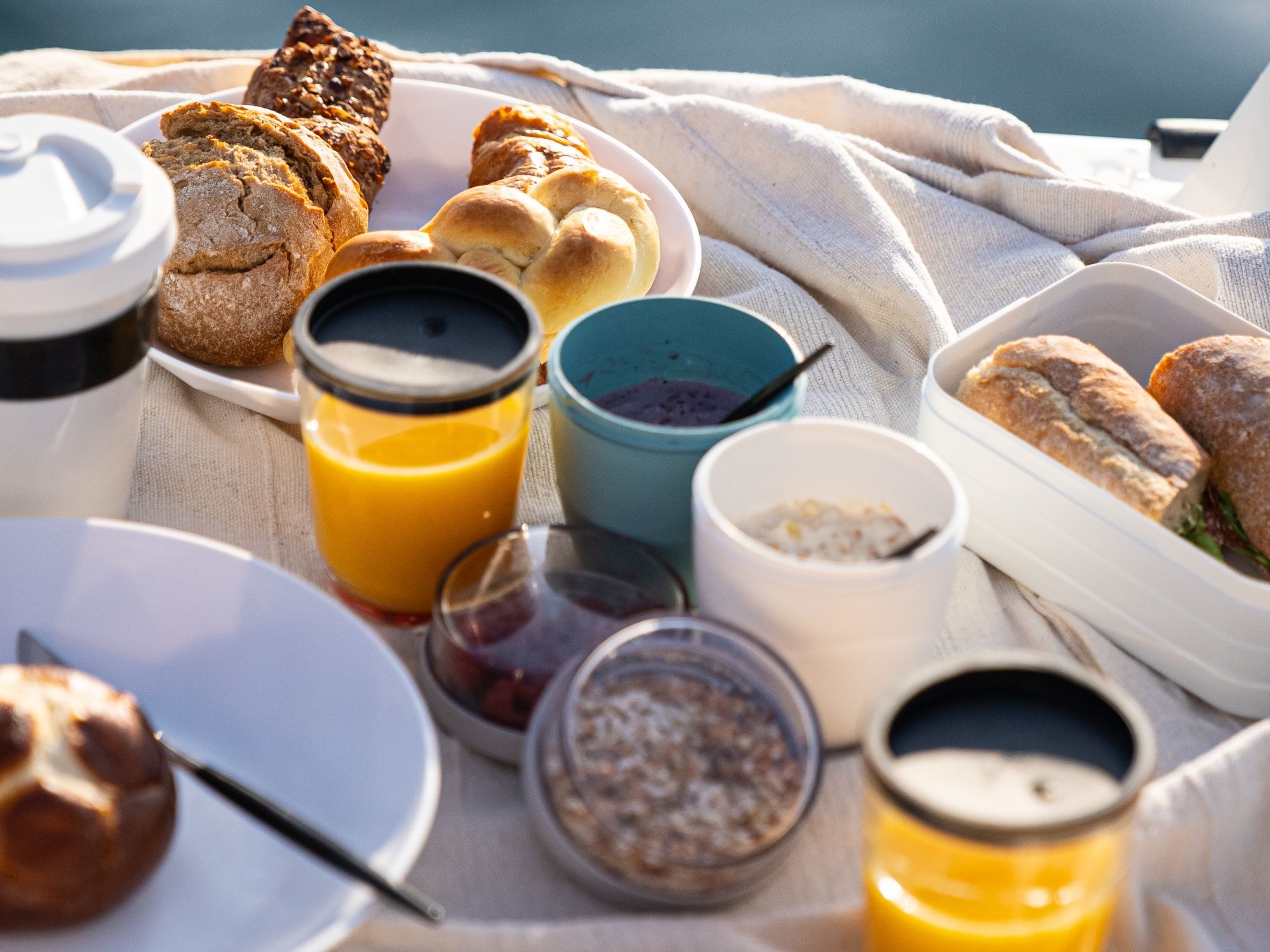 Pedálková snídaně s čerstvými rohlíky, džusem a jogurtem venku při letním počasí.