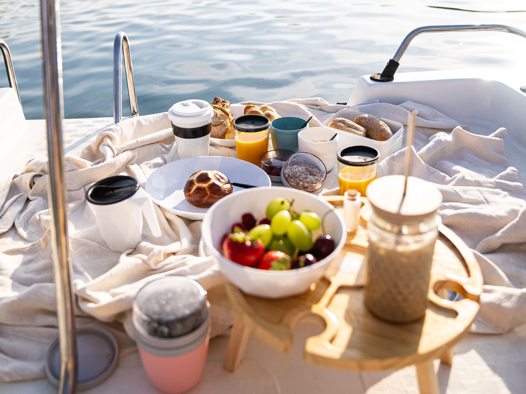 Veselá snídaně na paddleboardu s čerstvým ovocem, pečivem a nápoji na lodi v létě.
