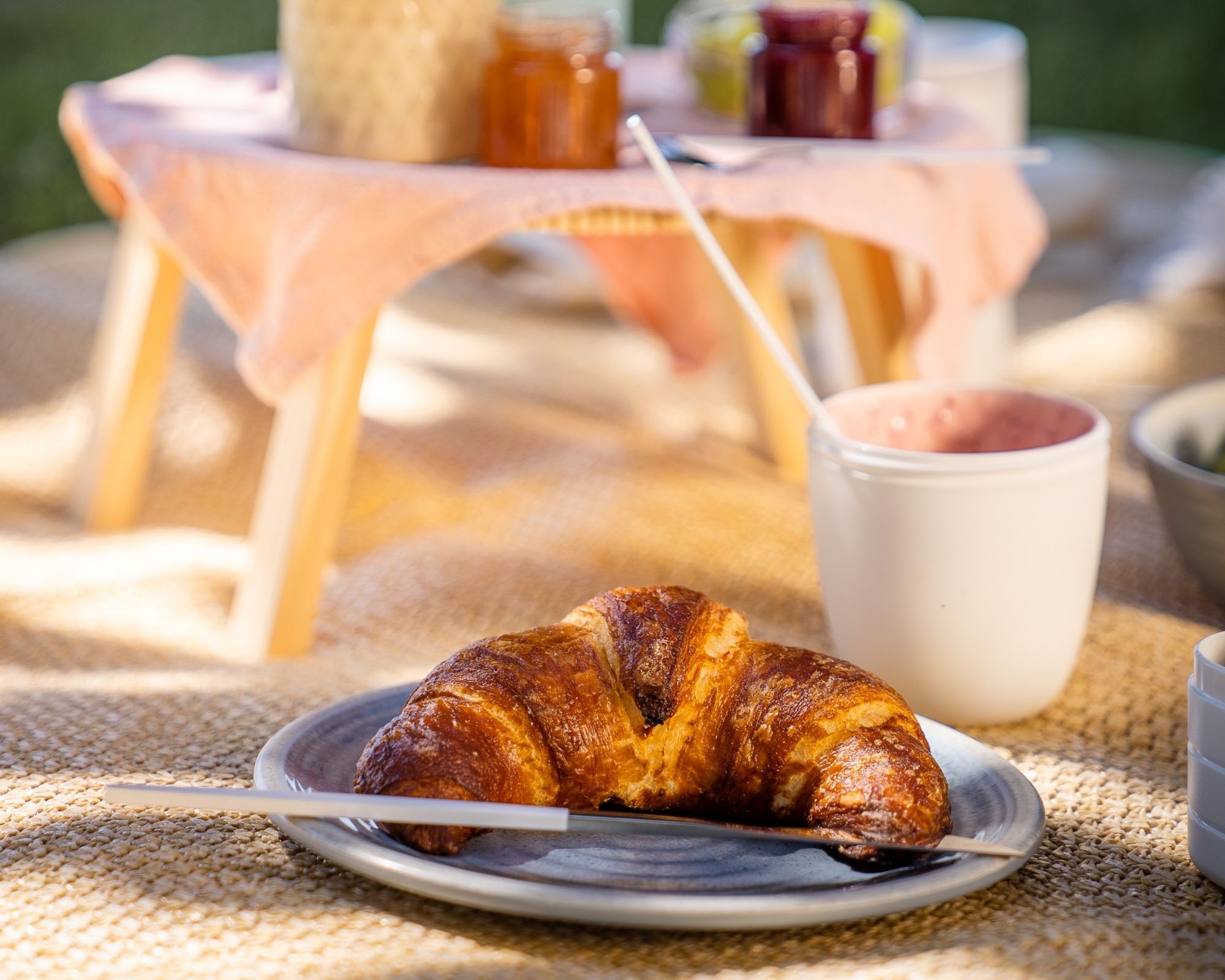 Colazione al parco con croissant e caffè, ideale per un picnic nel caldo estivo.