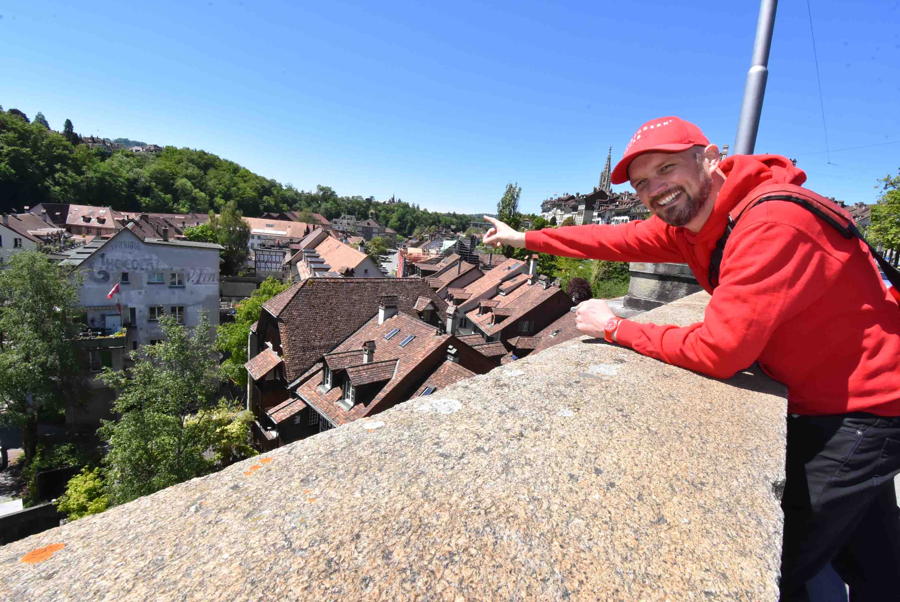 Schokoladen-Stadttour in Bern, Teilnehmer zeigt auf Dächer, klare Sicht.