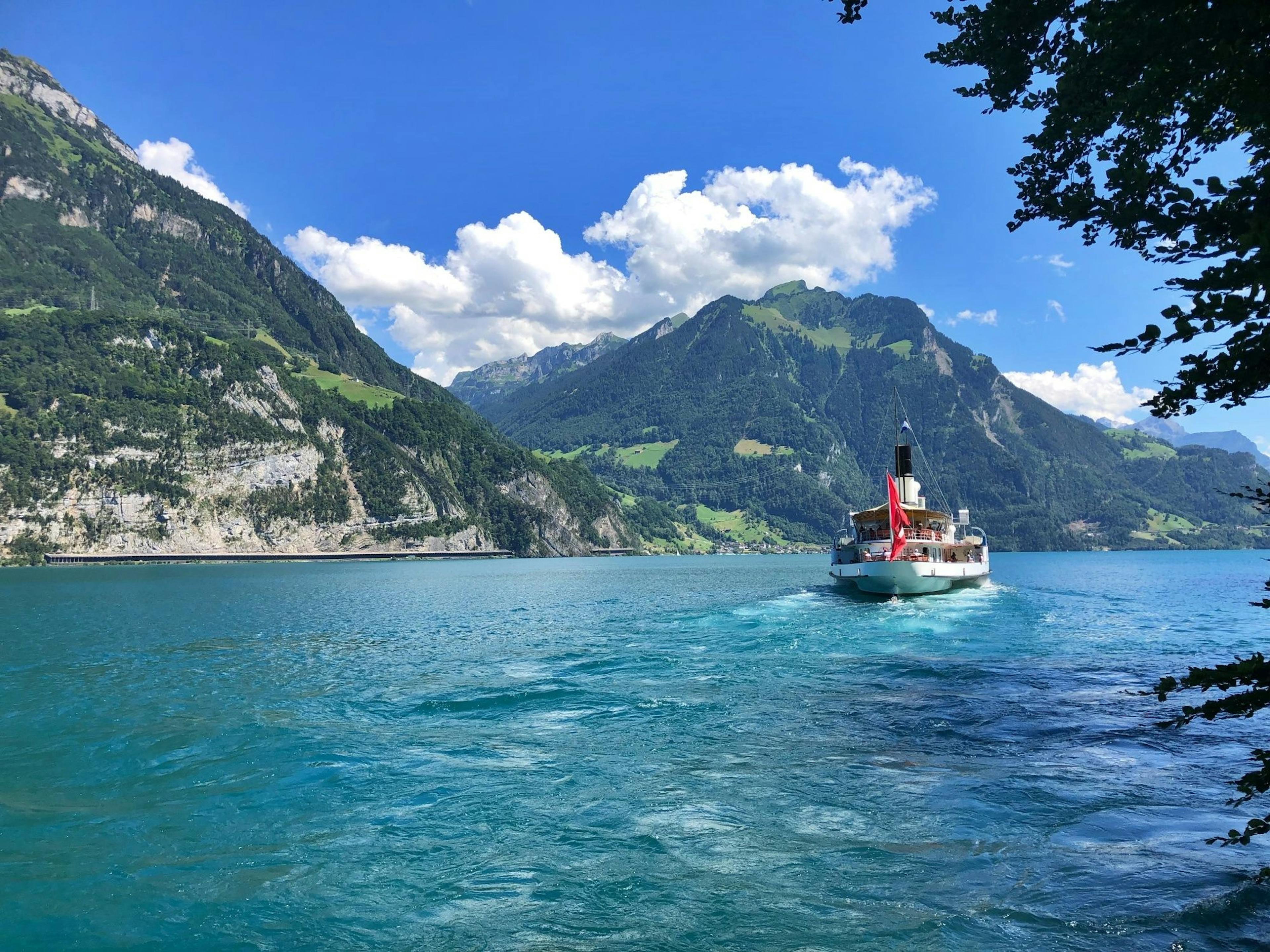 Dampfschiff auf dem Vierwaldstaettersee im Sommer, umgeben von Bergen und Natur.