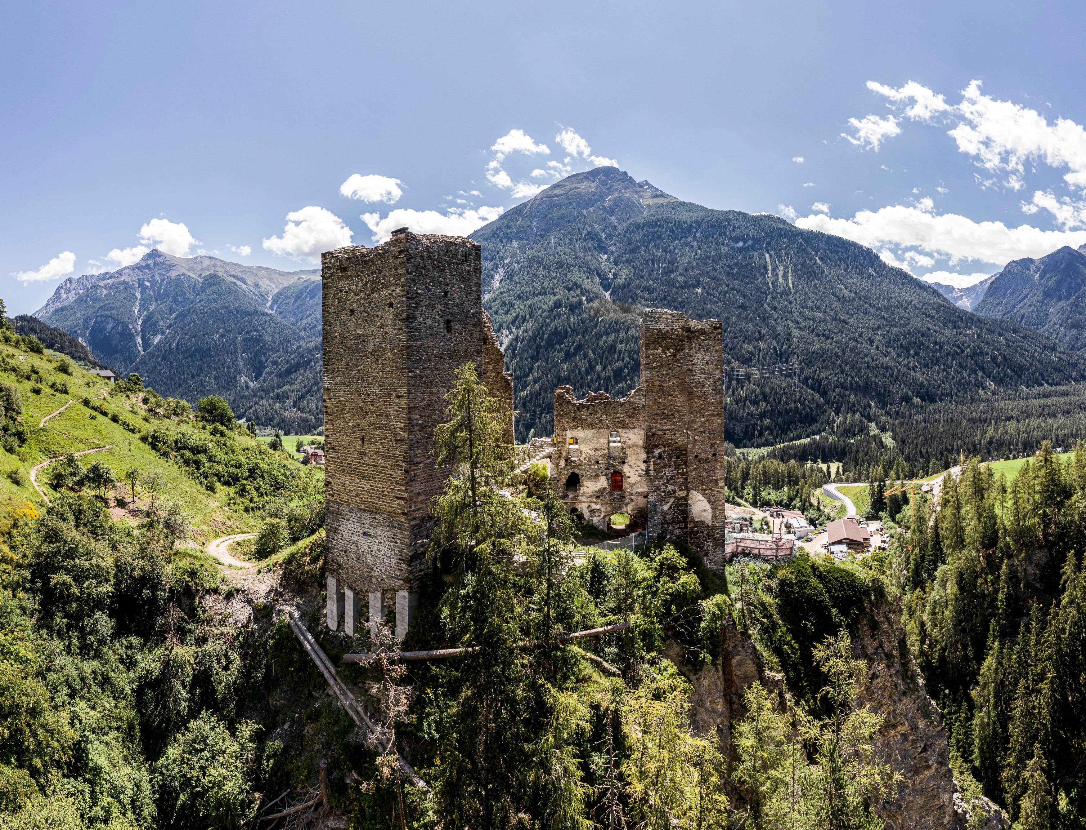Byvandring i Ramosch med historisk ruin, omgivet af natur og bjerge.
